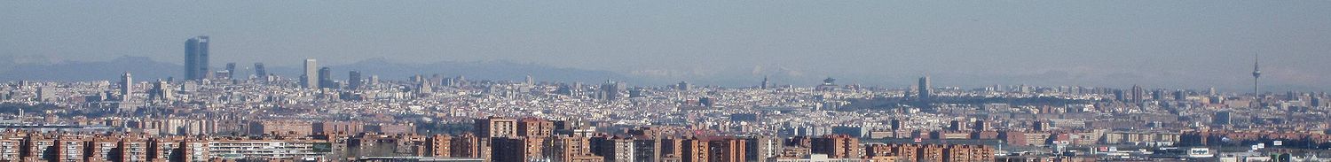 Vista de Madrid desde 15 km hacia el sur, concretamente desde el Cerro Buenavista, en el límite de los términos municipales de Leganés y Getafe. En este skyline destacan los rascacielos de CTBA y AZCA por ubicarse en la zona con más altitud de la ciudad y por formar dos agrupaciones de rascacielos de gran altura. A la derecha de estos dos complejos financieros se pueden apreciar el Parque del Retiro como una mancha verde y Torre España. Los rascacielos de la Plaza de España apenas sobresalen en el perfil por ubicarse en una zona de Madrid con una altitud relativamente baja.