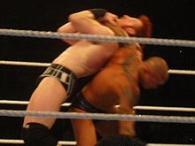 Orton aplicando un Inverted headlock backbreacker a Sheamus.