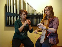 Mirta Caviello, tocando una flauta sopranino, y Marina Fernández tocando flauta de 3 orificios y Tambor de Bearn.